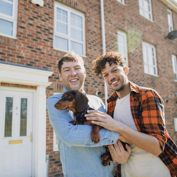 Couple outside new home with dog - stock