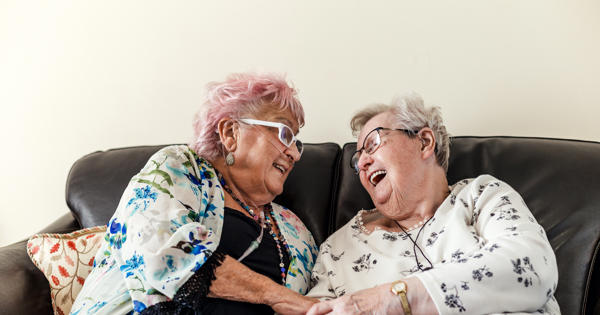 Older ladies laughing on sofa - stock