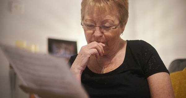 Older white woman reading a document looking pensive