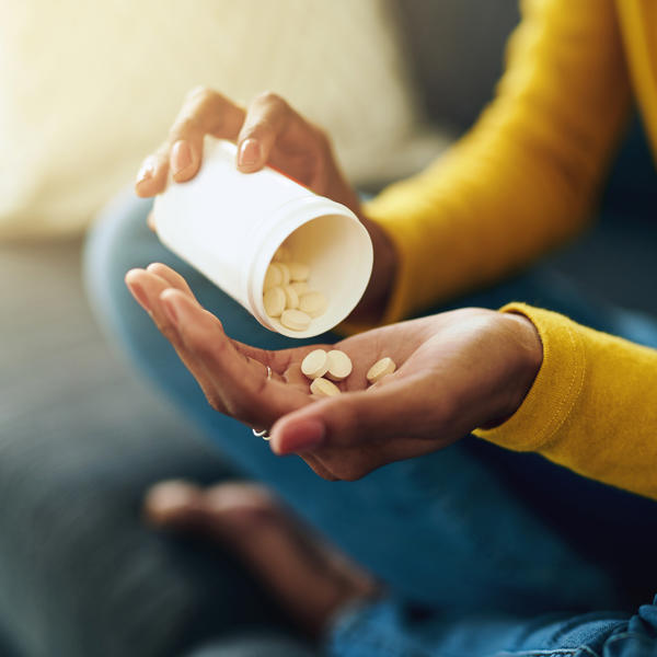 A close up of a person sat cross legged emptying pills into their hand