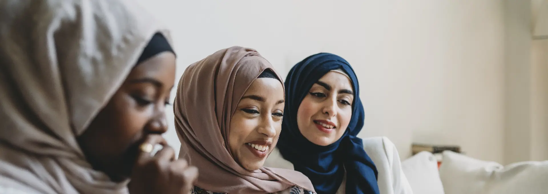 Three Muslim women smiling and using an ipad