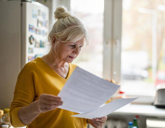 White women in yellow top reading paperwork looking confused